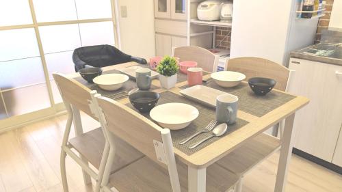 a table with bowls and utensils on it in a kitchen at 17min byCarTo Nagoya-Sta RoomB206 1parking Max5 Guest in Chiharachō