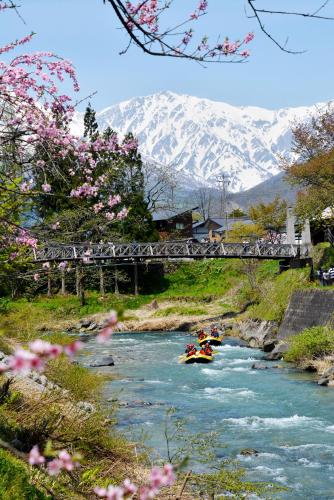 a bridge over a river with a boat on it at Hakuba Gateway Hotel in Hakuba