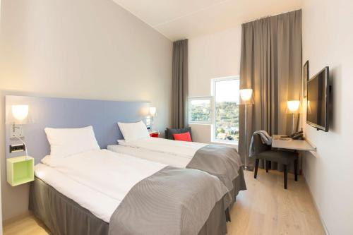 a hotel room with two beds and a desk at Scandic Lerkendal in Trondheim