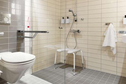 a bathroom with a shower with a toilet and a stool at Scandic Lerkendal in Trondheim