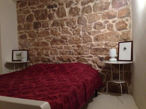 モーディカにあるLa Casa sulle Grotteの石壁のベッドルーム(赤いベッド付)