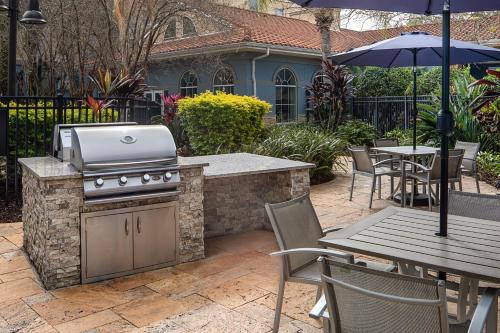 an outdoor grill with a table and an umbrella at Homewood Suites by Hilton Lake Buena Vista - Orlando in Orlando