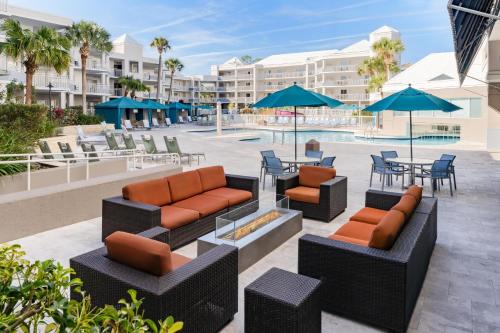 a patio with couches and chairs and tables and umbrellas at Embassy Suites by Hilton Orlando Lake Buena Vista Resort in Orlando