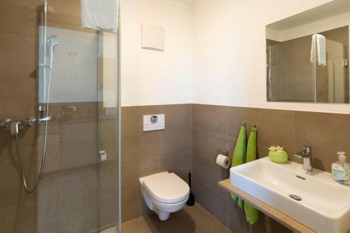 a bathroom with a toilet and a sink and a shower at Green Guest House in Wörth an der Isar