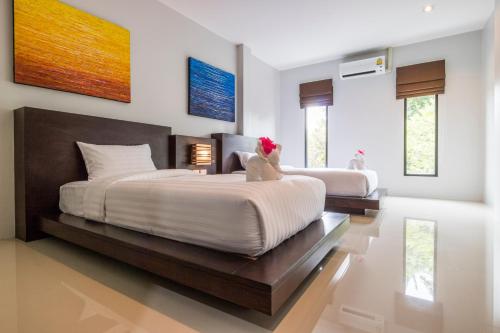 two beds in a bedroom with white walls and windows at S2 Residence in Ao Nang Beach