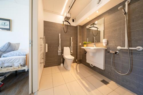 a bathroom with a sink and a toilet and a bed at Feriecenter Slettestrand in Fjerritslev