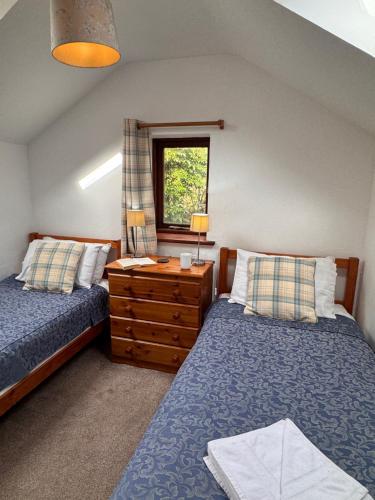 a bedroom with two beds and a dresser and a window at Upper Grippath Farm Holiday Cottages in Newport