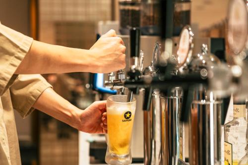 a person is holding a glass of beer at Richmond Hotel Premier Tokyo Schole in Tokyo