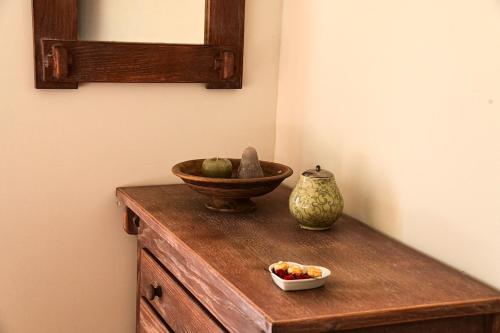 a wooden table with a bowl of fruit and a vase at Cosy farmhouse with sauna in Sint-Truiden