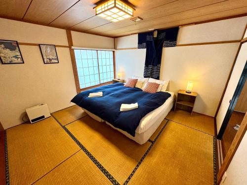 a bedroom with a large bed with blue sheets and pillows at Edo-Ko House in Myoko