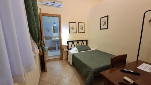 a small room with a bed and a desk and a table at Hotel del Centro in Palermo