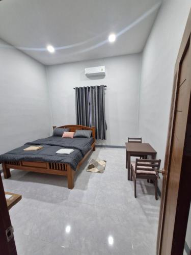 a bedroom with a bed and a table in it at NaklangHillHouse in Ko Lanta Yai
