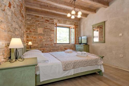 a bedroom with a bed and a brick wall at Villa Miranda Hvar in Stari Grad