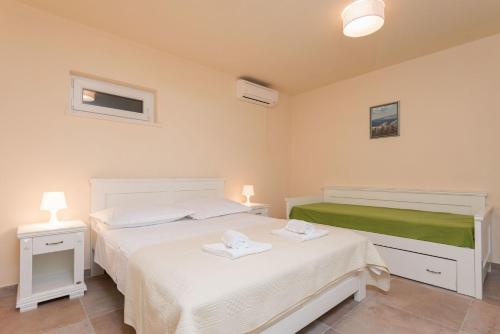 a bedroom with two beds with white sheets and a green blanket at House Sandra in Lumbarda