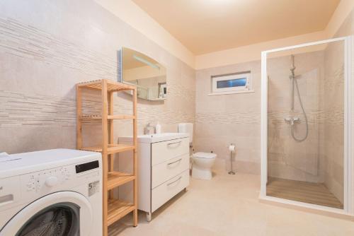 a bathroom with a washing machine and a shower at House Sandra in Lumbarda