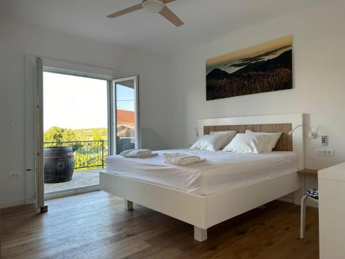 a white bedroom with a bed and a sliding glass door at House Pavicic in Poljica