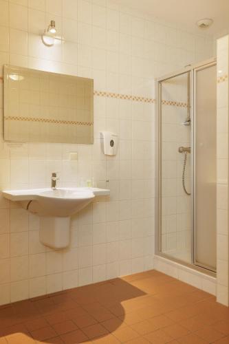 a bathroom with a sink and a shower at Hotel De Brabantse Biesbosch in Werkendam
