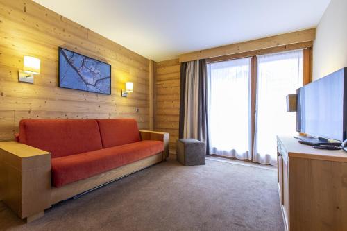 a living room with a couch and a television at Résidence Les Chalets du Forum - Courchevel 1850 in Courchevel
