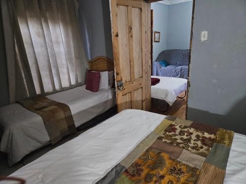 a small room with two beds and a door at Die Kliphuisie Gastehuis in Vryburg