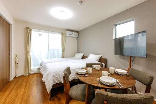 a room with a bed and a table and a tv at The Top名駅 in Nagoya