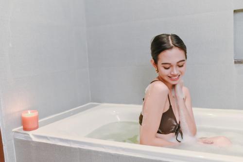 Eine Frau sitzt mit einer Kerze in einer Badewanne. in der Unterkunft The Tribute Hotel in Manila