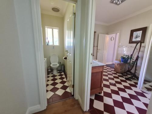 a bathroom with a toilet and a checkered floor at Birchwood Gardens Bed and Breakfast in Narrikup