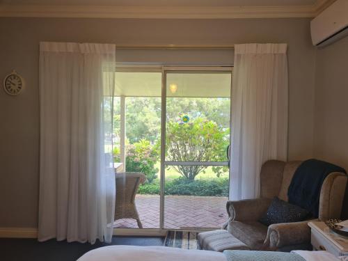 a living room with a couch and a sliding glass door at Birchwood Gardens Bed and Breakfast in Narrikup