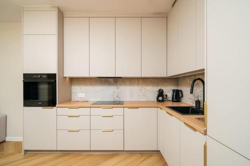 a white kitchen with white cabinets and a sink at Sand Boho Harmony Luxury - AC Parking & Balcony - by UniqueRent in Wrocław