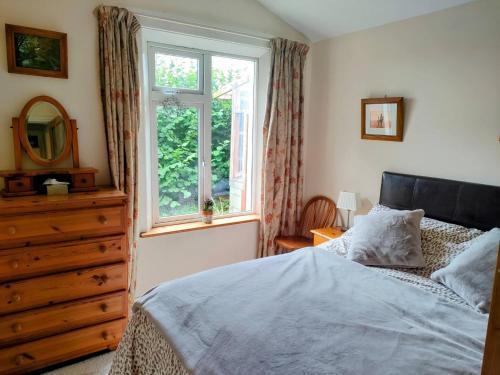 a bedroom with a bed and a dresser and a window at Hidden Hearts Haven Spa in Lelagh