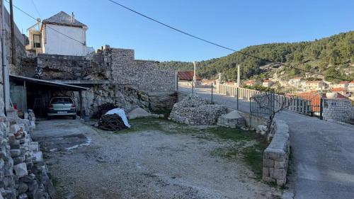 a building with a car parked next to a street at Visilo Heritage Stone House - A 300-year-old Legacy in the Heart of Pučišća in Pučišća