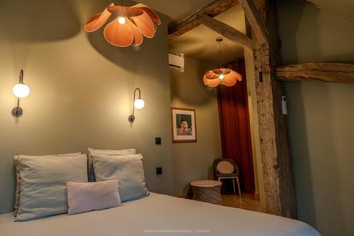 a bedroom with a bed with two pillows and two lights at La Grange de Léonie Chambres d'hôtes Piscine et Spa Calme et à 5min A71 A20 A85 in Vierzon