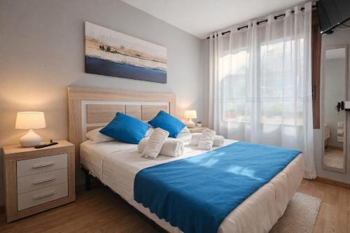 a bedroom with a bed with blue and white pillows at Casa Vacacional El Alisu in Arriondas