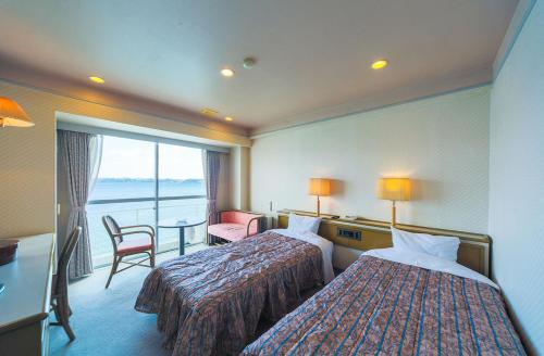 a hotel room with two beds and a balcony at Hotel Listel Hamanako in Hamamatsu