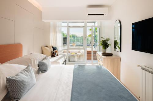 a bedroom with a bed and a living room with a tv at Hotel Waterman Kaktus in Supetar