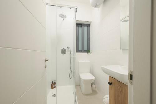 a white bathroom with a shower and a toilet at GOZO DIVE Residence in Xlendi