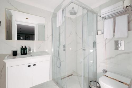 a white bathroom with a shower and a sink at DBD Hotel Çeşme in Yumru
