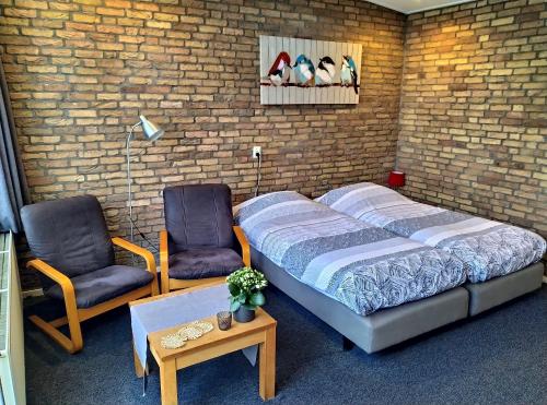 a bedroom with a bed and two chairs at Motel Paradiso in Bad-Nieuweschans