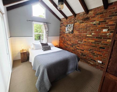 a bedroom with a bed and a brick wall at Cascade Cottage Circa 1840 in West Hobart