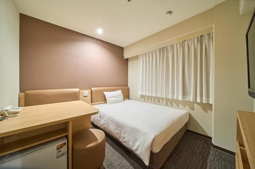 a small room with a bed and a desk at Via Inn Shin-Osaka West in Osaka