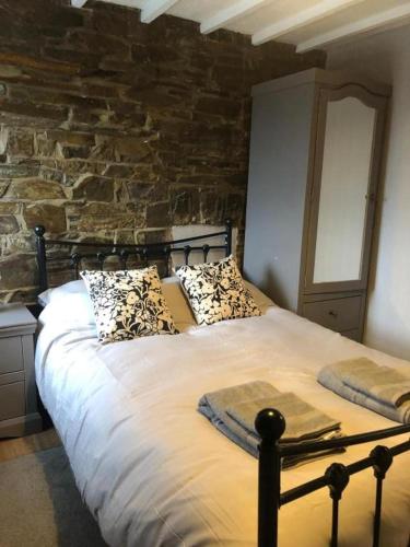 a bed in a room with a stone wall at Cosy Pubs Bed & Breakfast in Rhayader