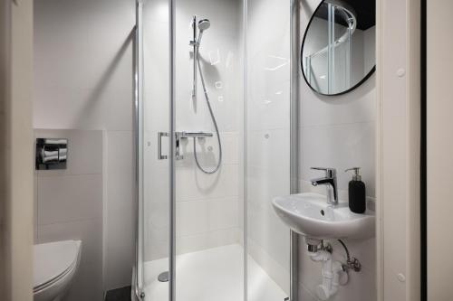 a white bathroom with a shower and a sink at BDSM Play Apartments in Vilnius
