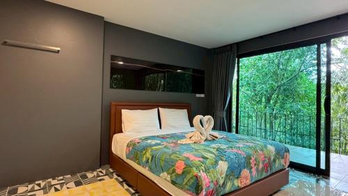 a bedroom with a bed and a large window at Khaolak Nature House in Khao Lak