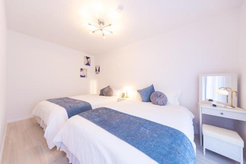 two beds in a room with white walls at Miraie Suzuka Kasado in Suzuka