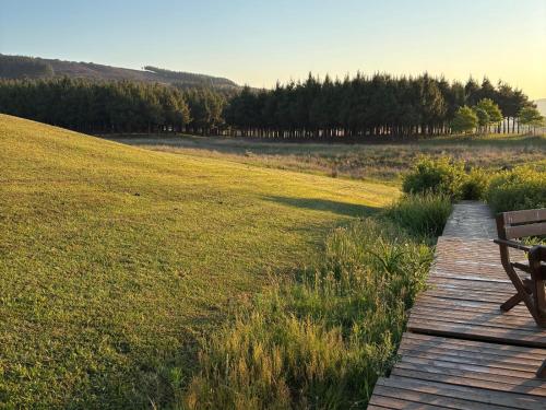 a wooden path through a field with a bench at Shiloh Lodges Tweefontein in Mooiriver