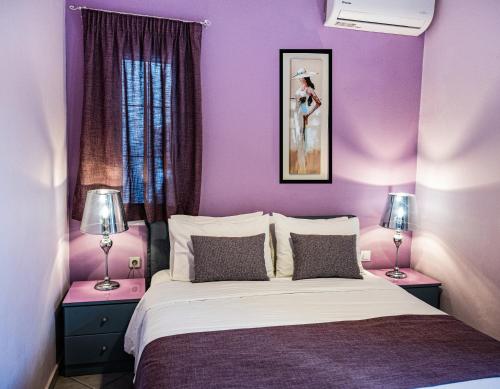 a bedroom with purple walls and a bed with two lamps at Sand Garden Apart, Easy Stay by Heraklion Coast in Ayía Marína