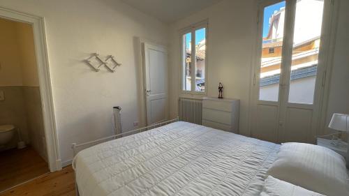 a white bedroom with a bed and two windows at Glicine in Stresa