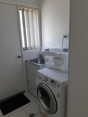 a laundry room with a washing machine and a sink at Luxurious 3 Bedroom Executive Home-Private Retreat in Higgins