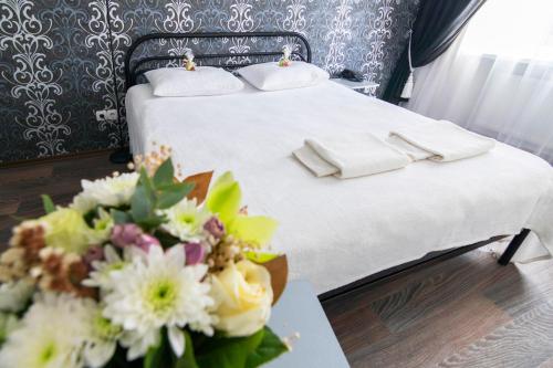 a bed with white sheets and a bouquet of flowers at Centralny Hotel in Kryvyi Rih