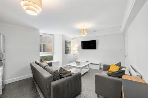 a living room with two couches and a tv at Commercial Street Residence in Dundee
