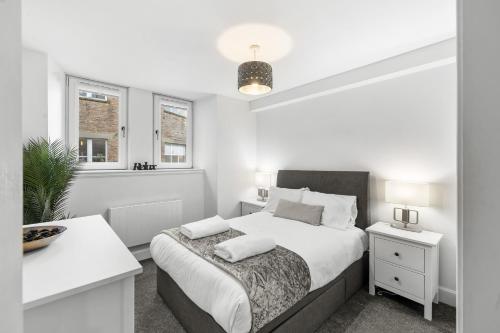 a white bedroom with a bed and two windows at Commercial Street Residence in Dundee